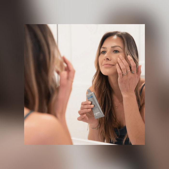 Woman in mirror adding cream to face