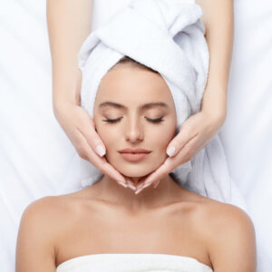 Therapist massaging face of beautiful woman during facial